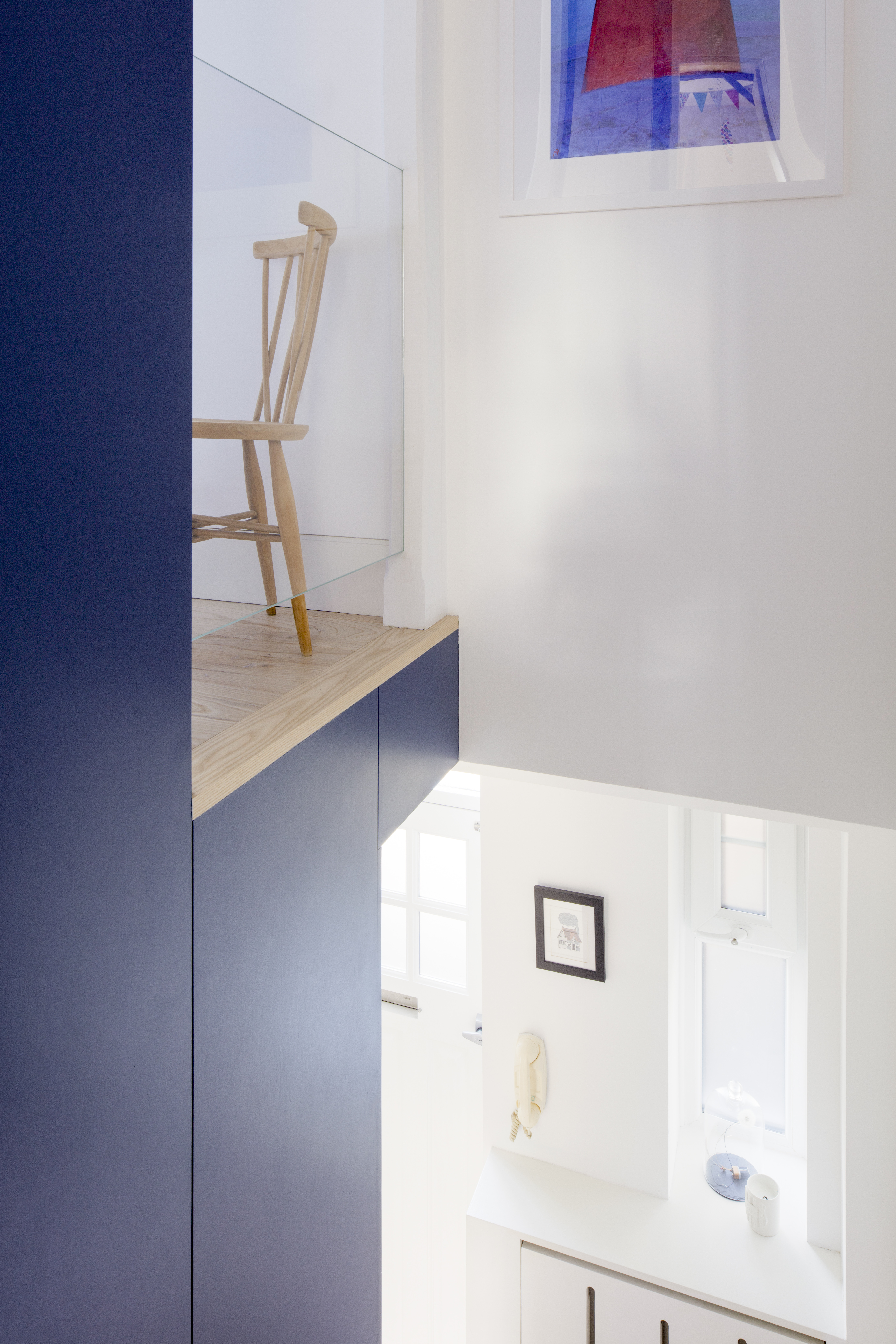 Multi-level transitional space with navy-blue fitted joinery and glass balustrade